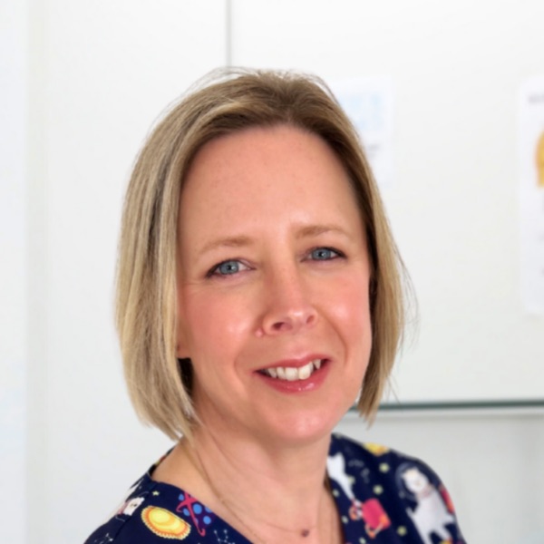 Kelly Taylor, stoma nurse, smiling, wearing navy patterned scrubs.